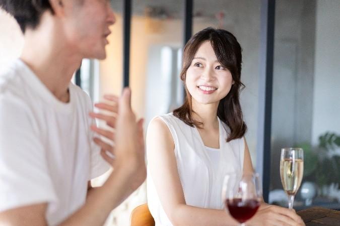 グラスを持って会話する男女の画像